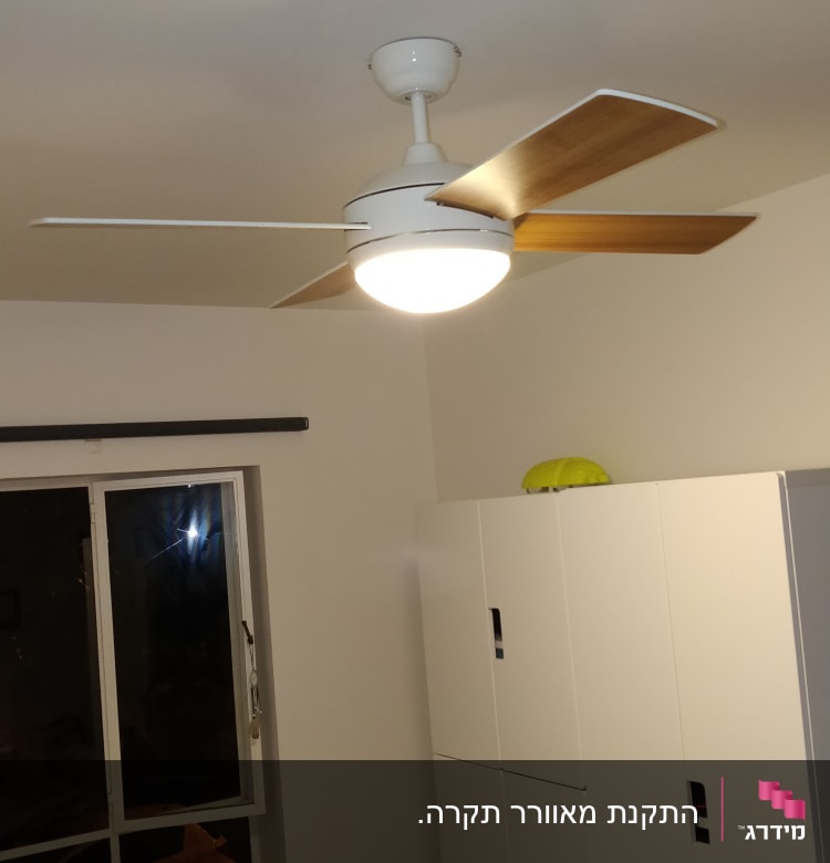 מאוורר תקרה עם תאורה מותקן בחדר